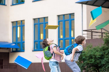 Happy children - two boys friends with books and backpacks on the first or last school day.