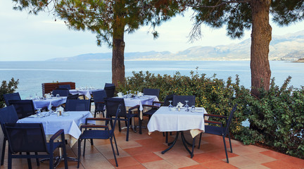 Restaurant with served table in seafront of Aegean sea in Hersonissos, Crete.