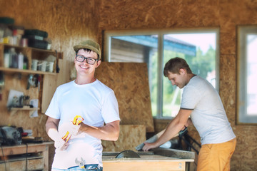 Adult young men, two workers working in a carpentry workshop with tools