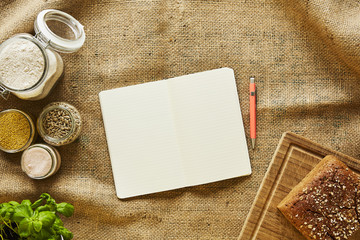 writing recipes in bakery scene notebook surrounded by ingredients for making bread