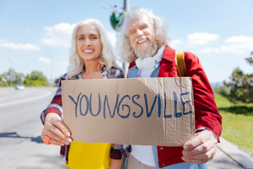 To Youngsville. Selective focus of a sign with an inscription being in hands of joyful non...