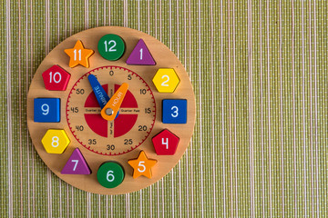 Wooden toy clock on a green, bamboo mat