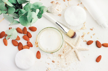 Fototapeta na wymiar Top view white cosmetic product ingredients, homemade rice water and nut milk facial lotion with almond. Homemade beauty treatment recipe. 