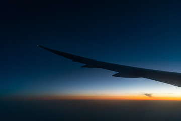 Silhouette wing of an airplane at sunrise view through the window.