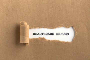 The text HEALTHCARE REFORM behind torn brown paper