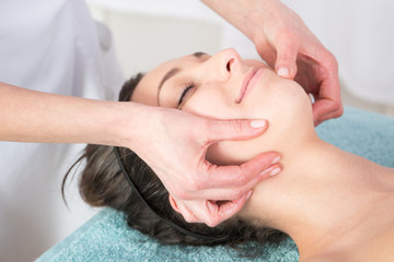 Fototapeta na wymiar Young woman enjoying face head massage in spa salon