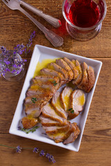 Sliced duck breast with orange sauce and thyme, glass of red wine. View from above, top studio shot