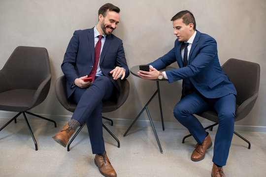 Trendy businessmen sharing smartphone in leisure - Powered by Adobe