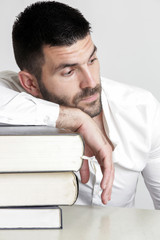 Naklejka premium Portrait of young handsome student with pile of books, education concept, studio isolated picture