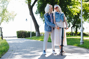 Unusual activity. Positive happy couple riding a scooter while having a walk together in the park