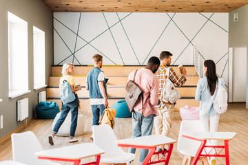 rear view of group of young students going out of lecture room in college