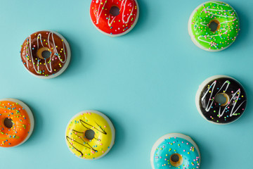 Fototapeta premium Creative arrangement of colorful donuts on pastel blue background. Minimal food concept. Flat lay.