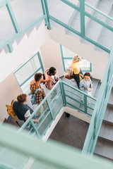 high angle view of group of young students walking down stairs at college
