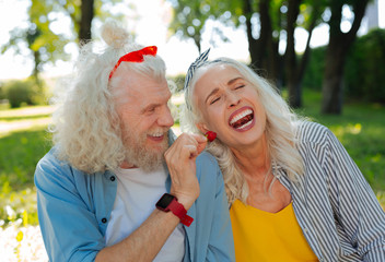 Fototapeta premium Do you want. Joyful happy man looking at his wife while offering her a strawberry