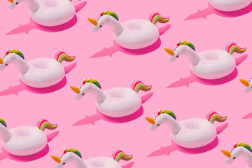 Inflatable unicorn pool toy pattern on pastel pink background. Minimal summer concept.