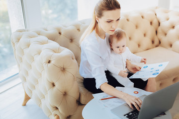 Modern technology. Attentive female person keeping diagram in left hand while staring at computer