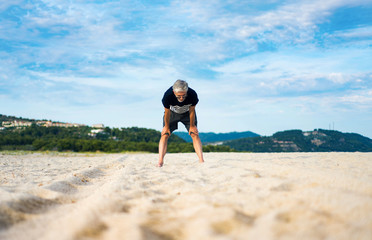 Tired senior taking rest during exercise on the beach
