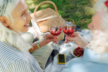 To us. Joyful nice couple cheering with wine while celebrating anniversary