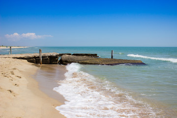 A beautiful sea view, a sandy beach and an old broken breakwater.