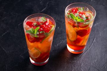 Strawberry mojito cocktail with berries, lime and mint. Summer berry cocktail on black background. horizontal