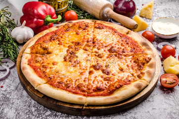 Homemade Meat Pizza Margarita with cheese, onions, tomatoes on a wooden board over stone table background, restaurant menu concept. Italian food style, close up.