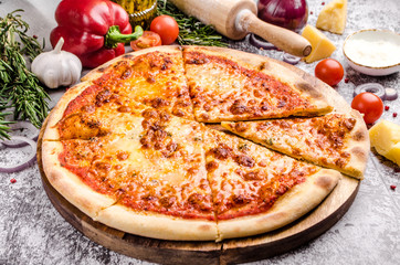 Homemade Meat Pizza Margarita with cheese, onions, tomatoes on a wooden board over stone table background, restaurant menu concept. Italian food style, close up.