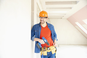 Handyman using hammer drill driver on construction site