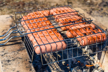 Sausages cooking in a barbecue grill on campfire
