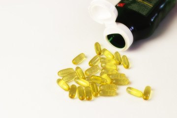 Cod liver oil omega 3 gel capsules on white background with bottle. Space for text