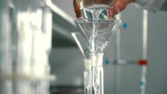 Chemist pouring alcohol into a flask through funnel
