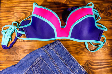 Female swimming suit and denim shorts on a wooden table