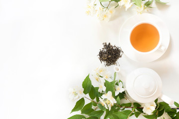 Obraz na płótnie Canvas Green jasmin tea and jasmine flowers, cup of green tea on white. Top view. Teatime.