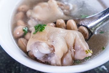 Taiwan's distinctive famous snacks: Peanut pork knuckle(pig's trotter) soup in a white bowl on stone table, Taiwan Delicacies, Taiwan Street Food
