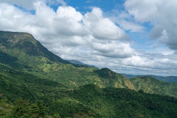 Scenic view of a Green mountains landscape with sunlight through beautiful mostly clouds on blue sky.