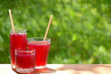 A few misted glasses with a summer drink from fresh berries on a greenery background with bokeh