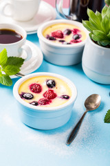 Berry clafouti. Traditional french sweet fruit dessert clafoutis with raspberries and blueberries on blue pink background. Healthy gluten free food concept with copy space.