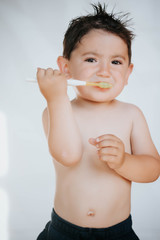 Kid learning how to stay healthy. Health care concept.Little boy brushing his teeth on white background