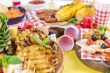 Different fruits and vegetables are cooked on the grill. Yellow background. Summer dinner. . Copy space.