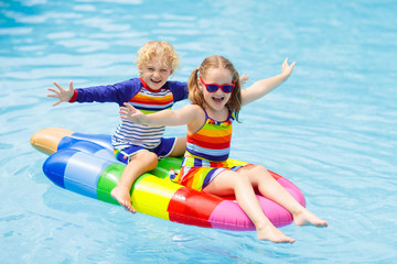 Kids on inflatable float in swimming pool.