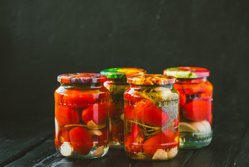 Several jars of canned tomatoes with ripe tomatoes and garlic