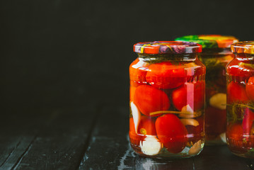 Several jars of canned tomatoes with ripe tomatoes and garlic