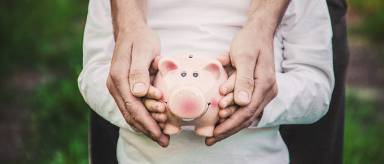 The child and parents are holding a piggy bank in their hands. Selective focus. 