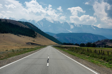 Naklejka premium Road asphalt path at the background of the high snow mountain ranges 