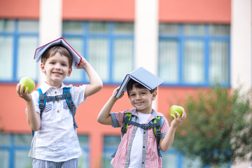 Child going to school. Boy and his friend holding books on head like house roof on the first school...