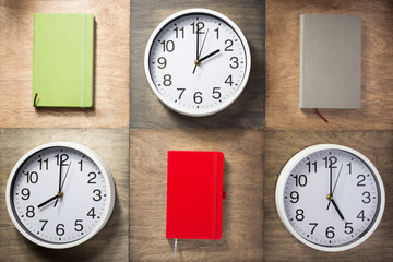 notebook and wall clock at wooden background