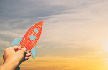 image of male hand holding a rocket against the sky. imagination and success concept.