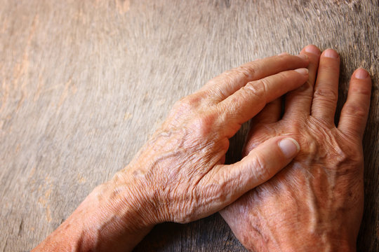 close up image of senior male hands over wooden table.