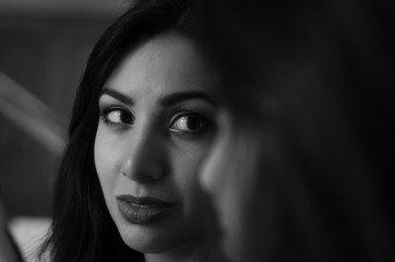 Fototapeta premium Young charming brunette girl looks at her reflection in the mirror