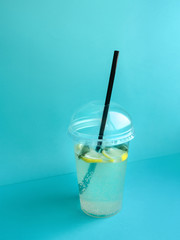 Glass of lemonade Plastic glass of lemonade and black straw on blue background Photo mockup with copy space