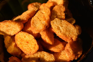 In a black transparent glass plate are dry crumbs of sliced dry baguette with taste and aroma of tomato and greens with salty rays